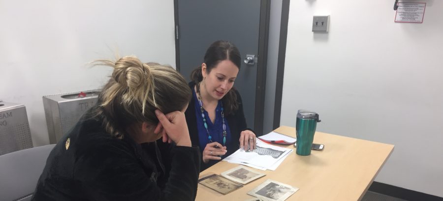 This is a photograph of two students in a classroom looking at and talking about historic photographs together.